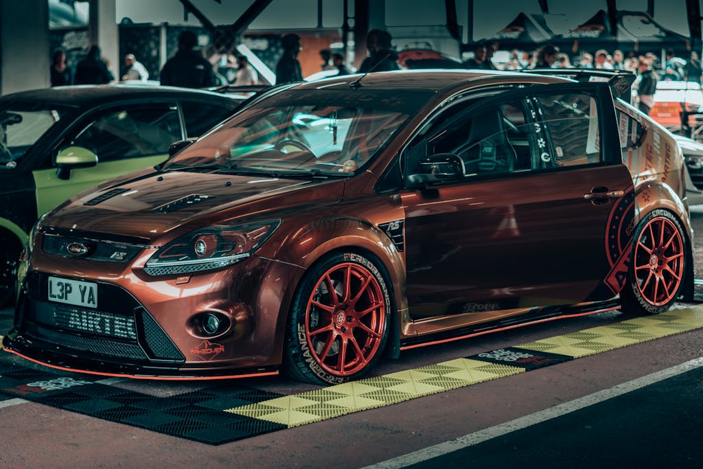 Modderguy A sleek brown Ford sports car with custom tuning displayed at an automotive event.